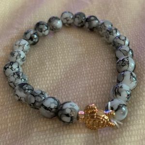 Black and white stretchy beaded bracelet with faux gold turtle charm.